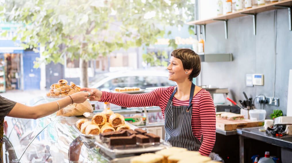 Cafe worker behind counter giving a customer their change