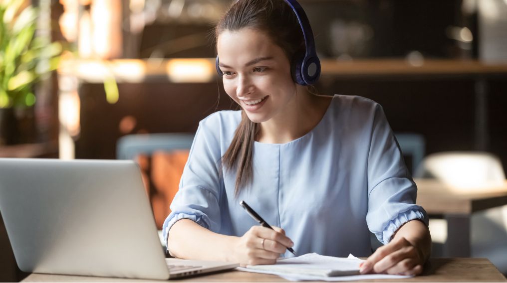 Person at work using their laptop and headphones taking down instructions